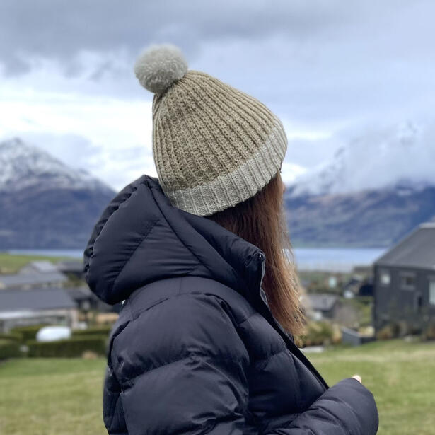 Women wearing a hand knitted beanie of cream and buttermilk with pom pom