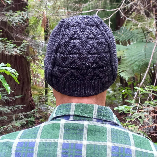 Man wearing a black hand knitted beanie standing in the forest